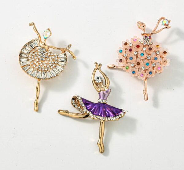 A set of three ballerina brooches on a white surface.