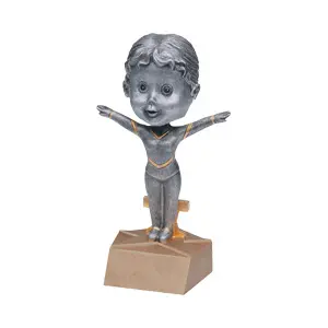 A silver figurine of a person standing on one foot.