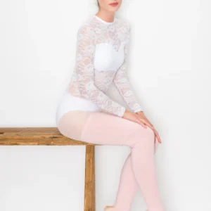 Ballet dancer in white lace leotard and pink tights sitting on wooden bench.