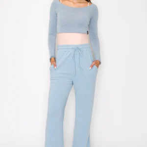 Woman wearing light blue loungewear with a pink waistband.