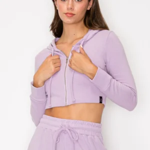 Young woman wearing a lavender cropped hoodie and matching pants.
