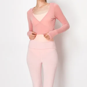 Woman in a pink fitted top and matching pants against a white background.