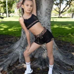 Young girl posing confidently by a large tree outdoors.