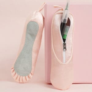 Pink ballet pointe shoes with cushioned insoles against a pale pink background.