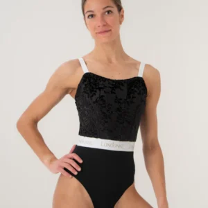 Woman posing in a black and white leotard against a plain background.